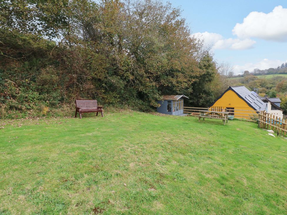 A garden with a bench and a shed at Pendre Barn Star near Cenarth
