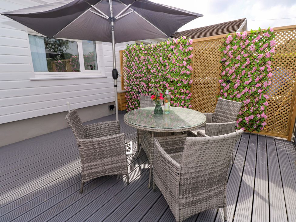 An outdoor seating area with a table and chairs at Pinecroft Annex Stepaside near Saundersfoot