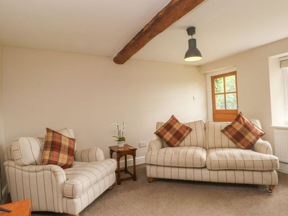 A living room with a sofa and armchair at Cottage Round T'Corner in Holmfirth