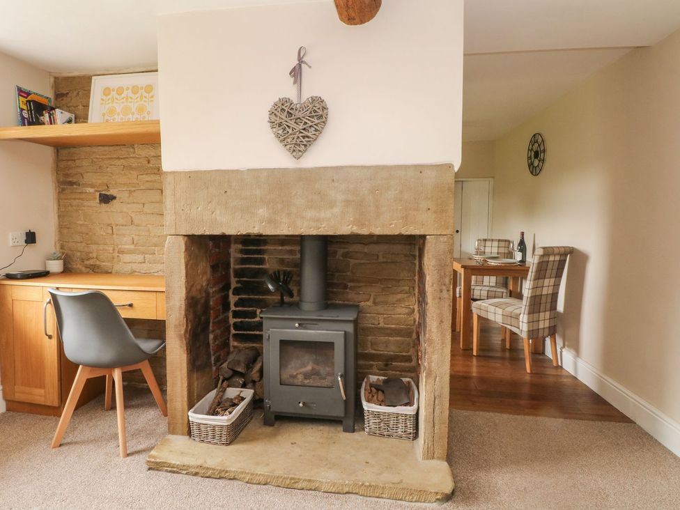 A living room with a fireplace and desk at Cottage Round T'Corner in Holmfirth