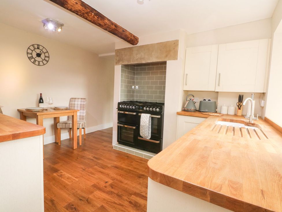 A kitchen with a dining table and oven at Cottage Round T'Corner in Holmfirth