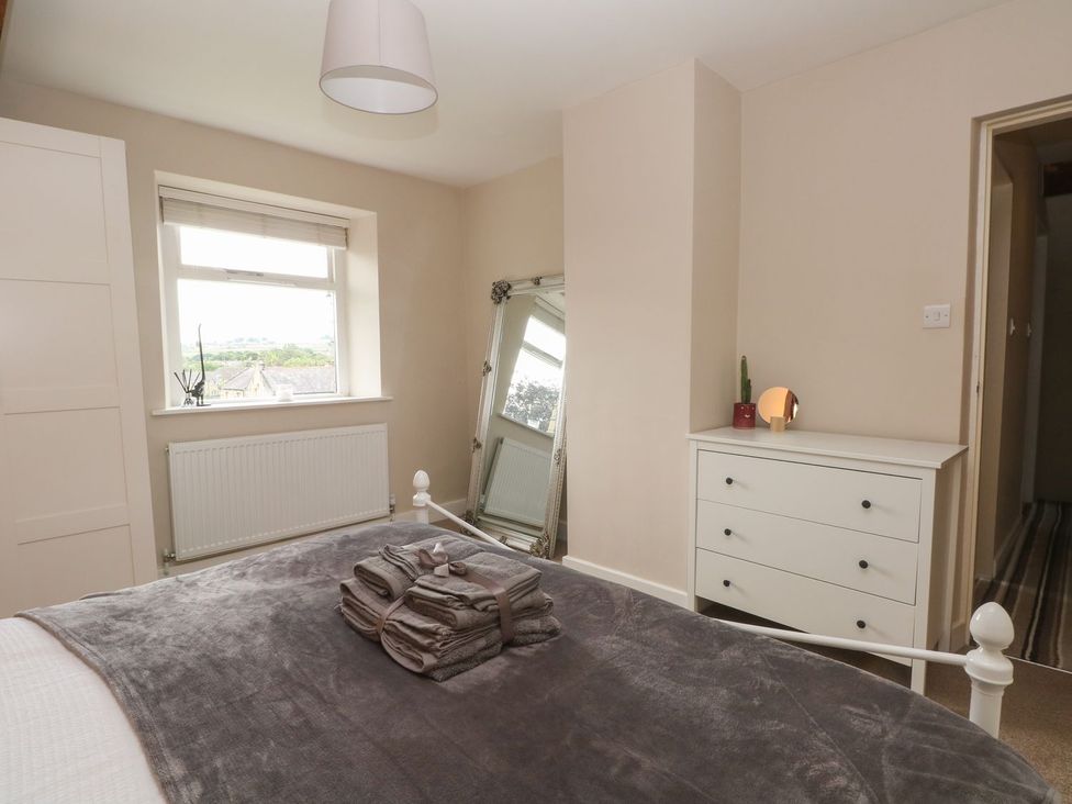 A bedroom with a bed and a mirror at Cottage Round T'Corner in Holmfirth