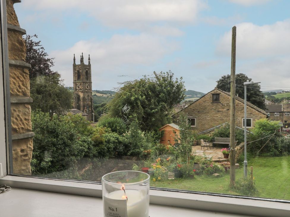 A view of a garden and church tower from a window at Cottage Round T'Corner in Holmfirth