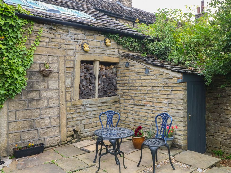 An outdoor seating area with a table and chairs at Cottage Round T'Corner in Holmfirth