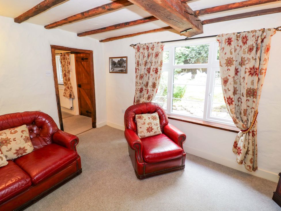 A living room with two red armchairs and a window at Fern Cottage in 