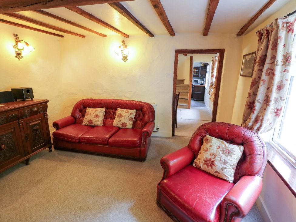 A living room with a red sofa and armchair at Fern Cottage