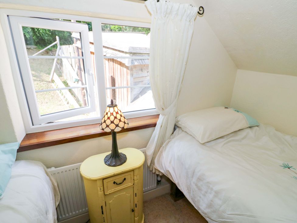 A bedroom with two beds and a lamp on a table at Fern Cottage 