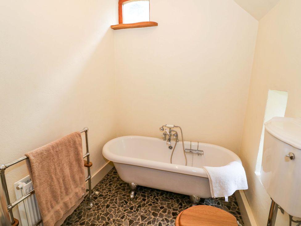 A bathroom with a bathtub and towel rack at Fern Cottage in 