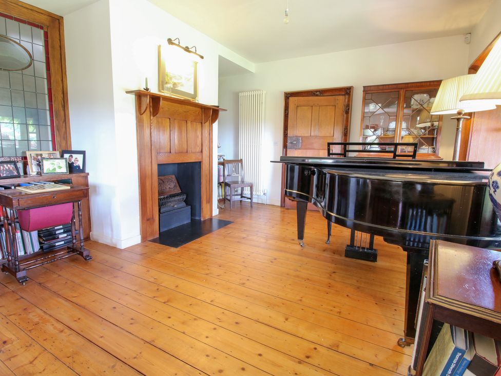 A living room featuring a piano and fireplace at Uplands House in Ledbury