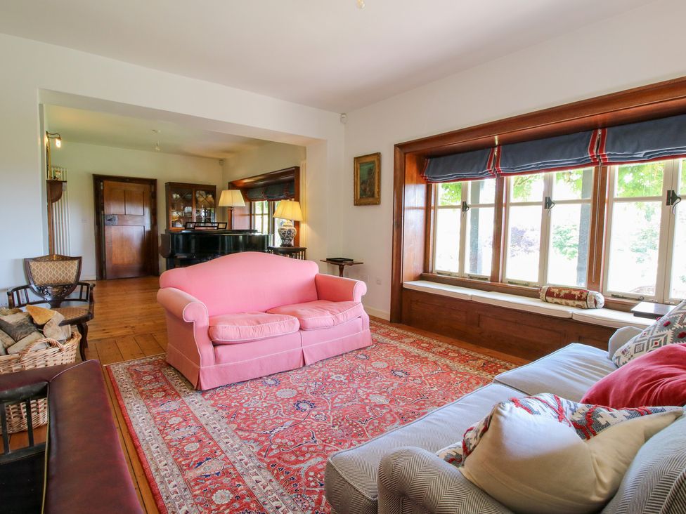 A living room featuring a pink sofa and piano at Uplands House in Ledbury
