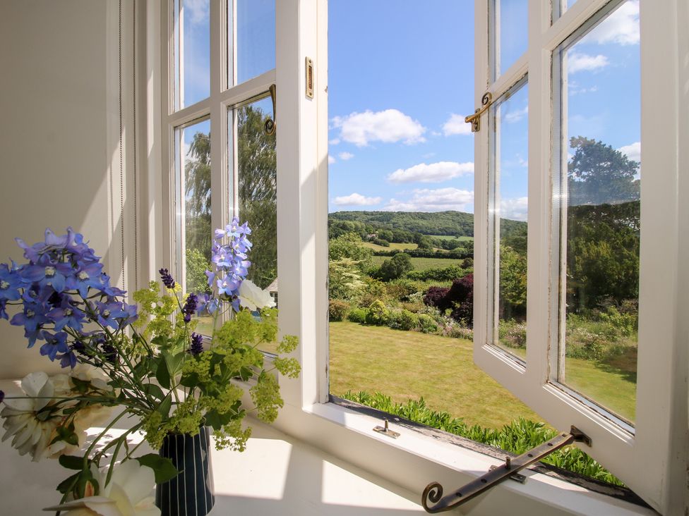 A window with flowers overlooking a valley at Uplands House Ledbury