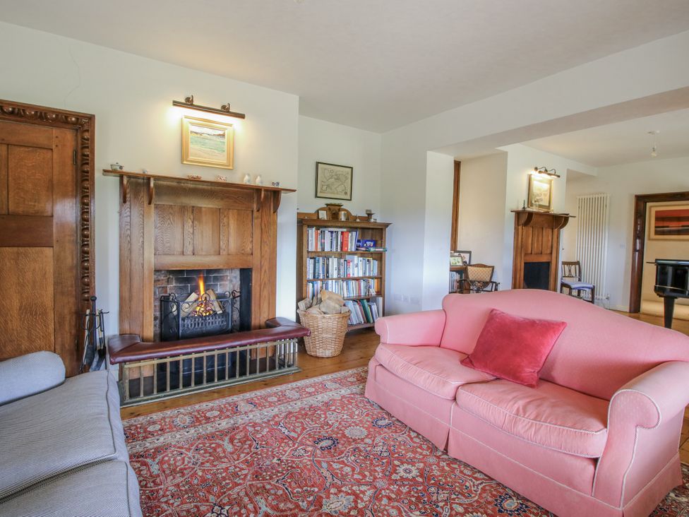 A living room with a fireplace, bookshelves, and sofas at Uplands Dowerhouse in Wellington Heath near Ledbury