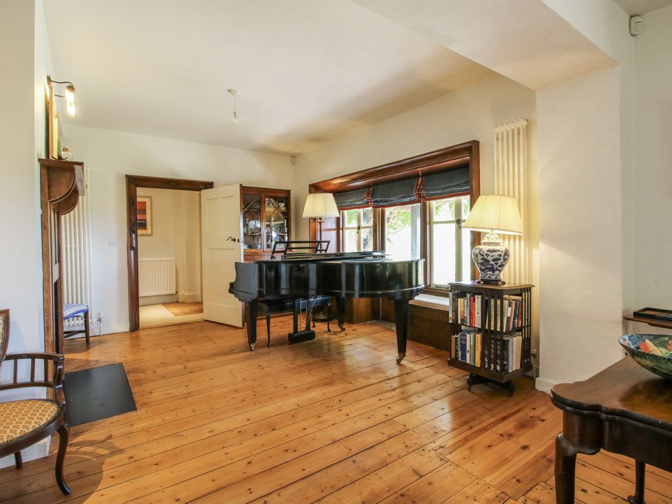 A living room with a piano and bookshelf at Uplands Dowerhouse Wellington Heath near Ledbury