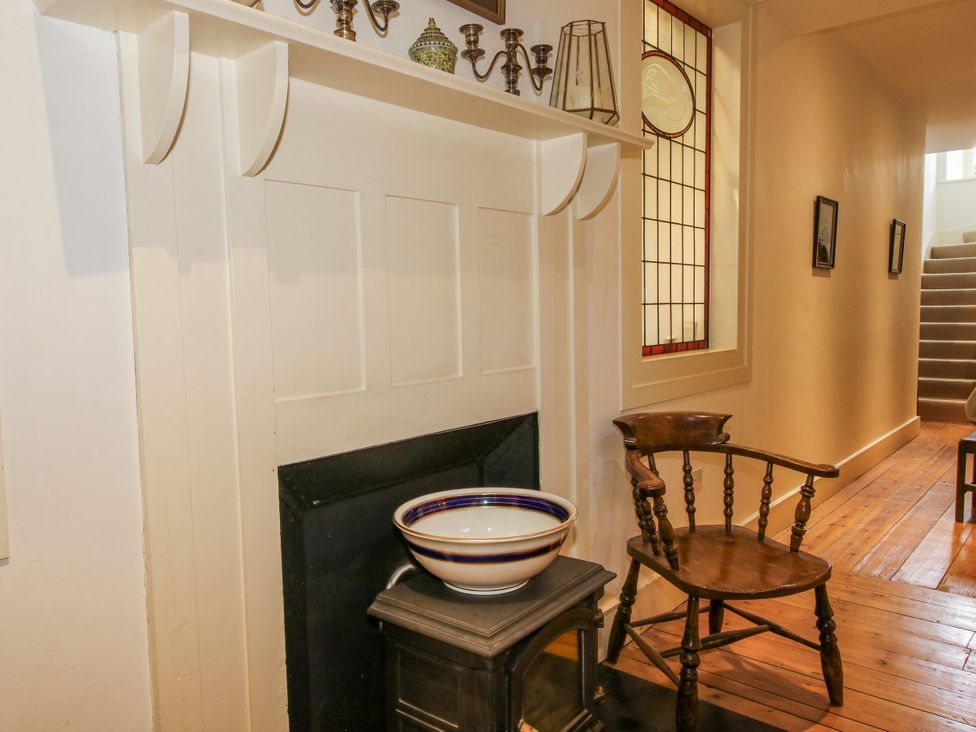 A hallway with a fireplace and wooden chair at Uplands Dowerhouse Wellington Heath near Ledbury