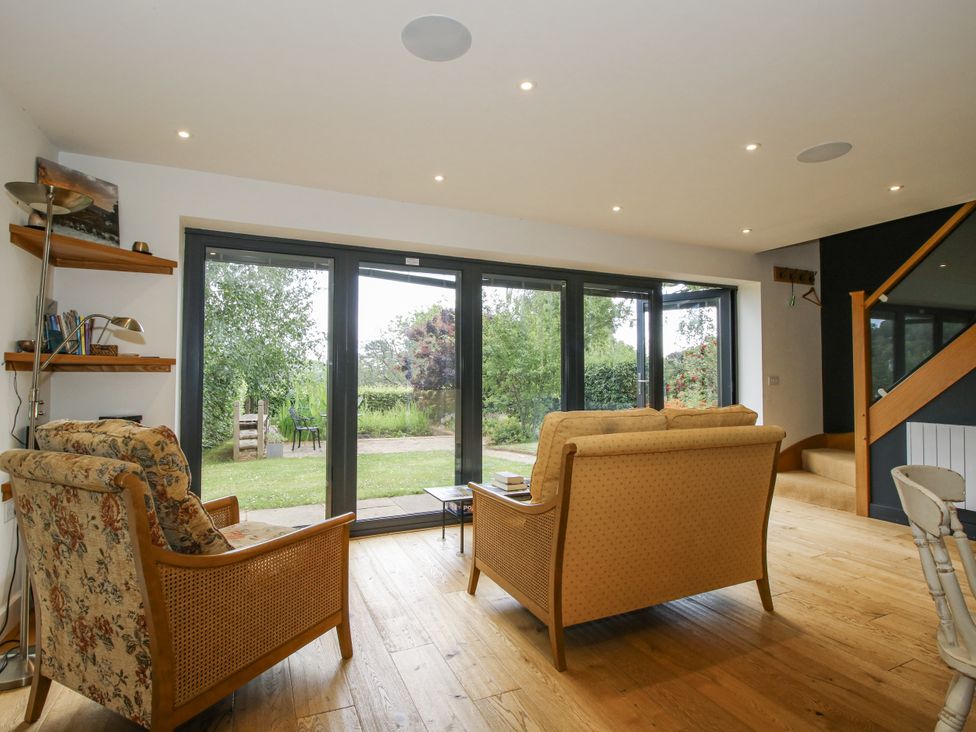 A living room with a sofa and garden view at Garden Cottage in Wellington Heath near Ledbury