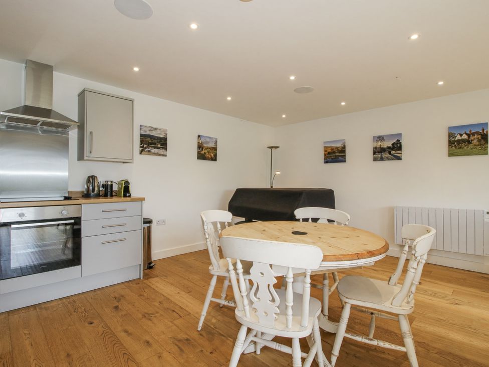 A kitchen with a dining area featuring a wooden table and chairs at Garden Cottage Wellington Heath near Ledbury