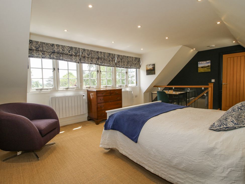 A bedroom with a bed and a chair at Garden Cottage in Wellington Heath near Ledbury