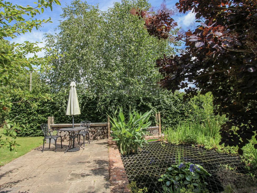 A garden with a table and chairs and a pond at Garden Cottage in Wellington Heath near Ledbury