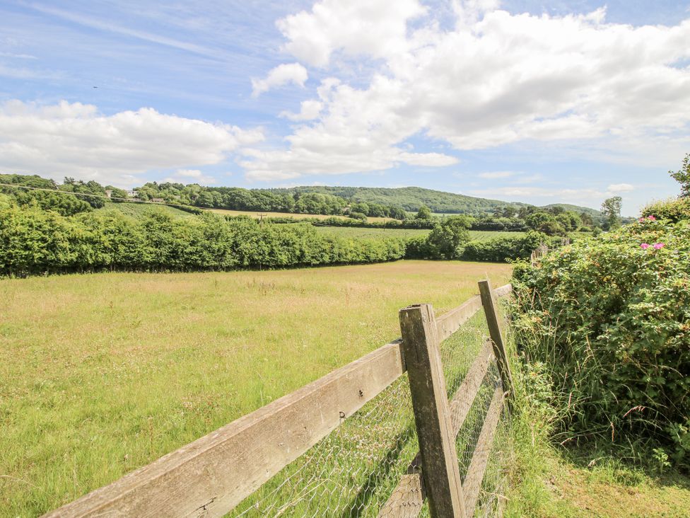 A field with a wooden fence and trees at Garden Cottage in Wellington Heath near Ledbury