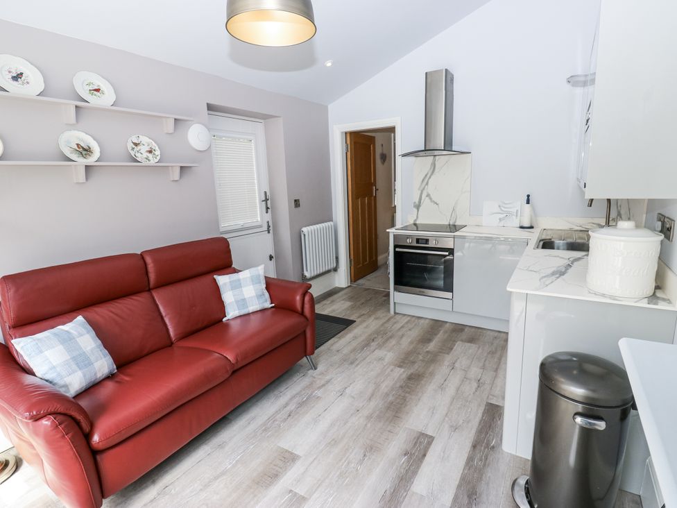 A kitchen with a red sofa and modern appliances at Little Birchinlea in Glossop
