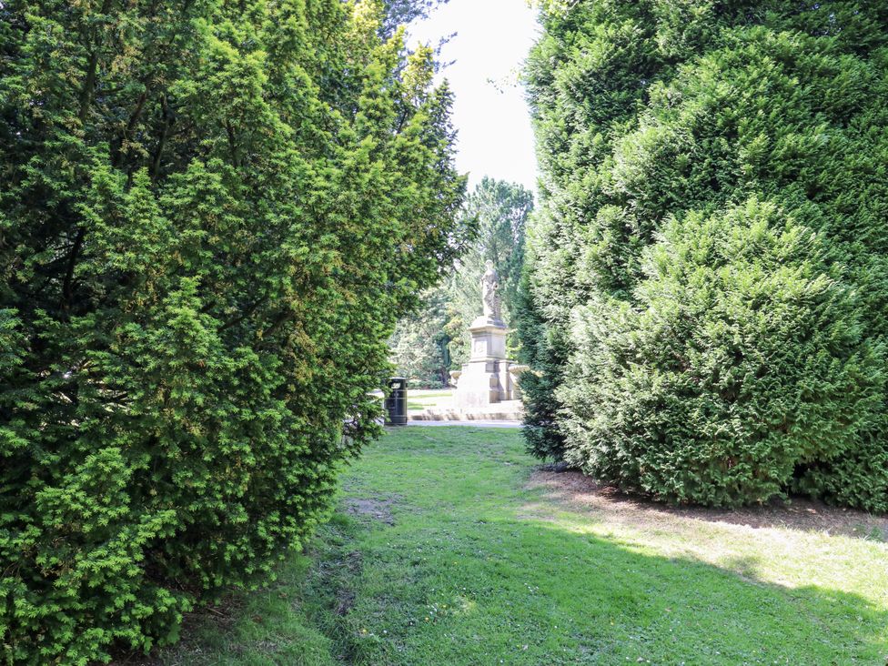 A garden with green trees and a statue at Little Birchinlea in Glossop