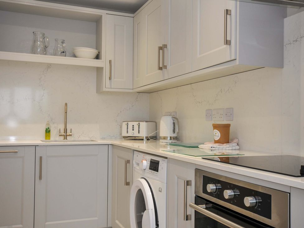 A kitchen with cabinets, sink, kettle, and washing machine at Evelyn in Looe