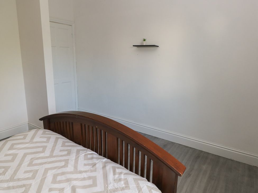 A bedroom with a bed and a shelf on the wall at Maes Hyfryd in Clynderwen