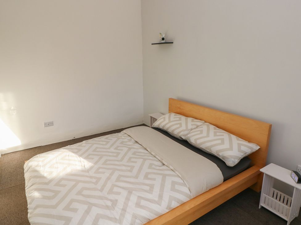 A bedroom with a bed and nightstand at Maes Hyfryd Clynderwen