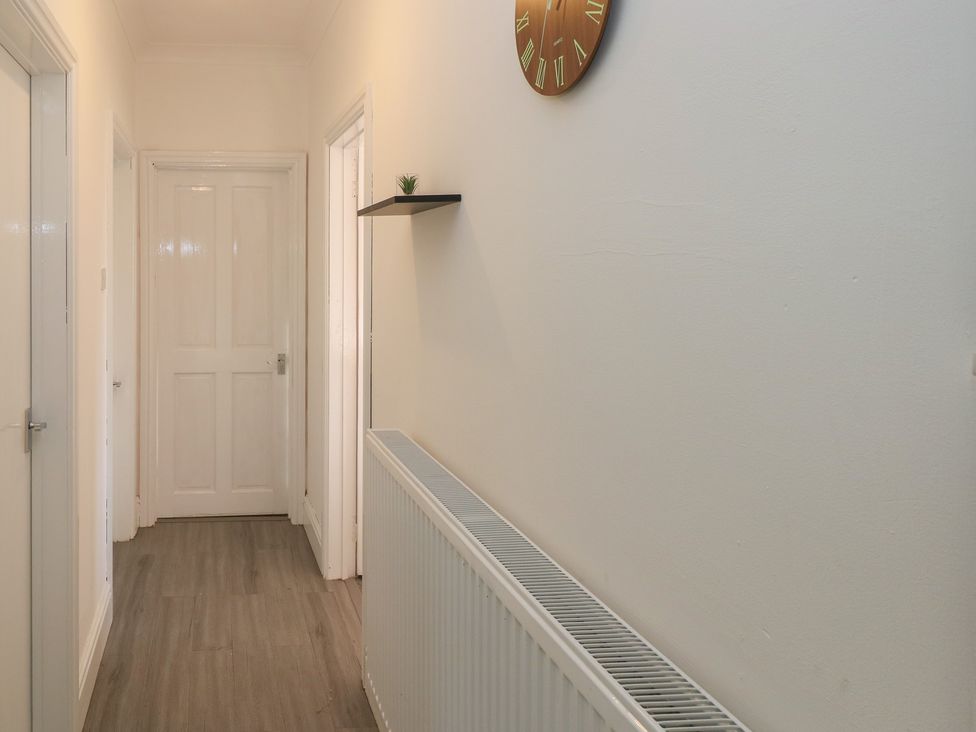 A hallway with a radiator and a wall clock at Maes Hyfryd in Clynderwen