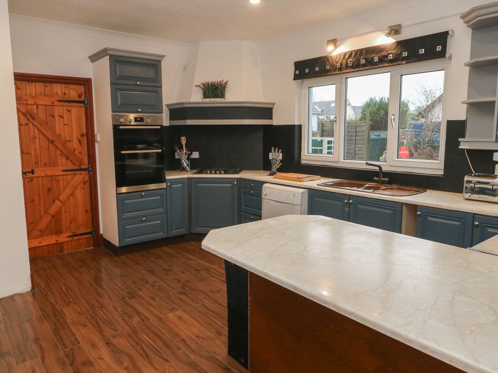 A kitchen with cabinets, sink, and oven at Maes Hyfryd in Clynderwen