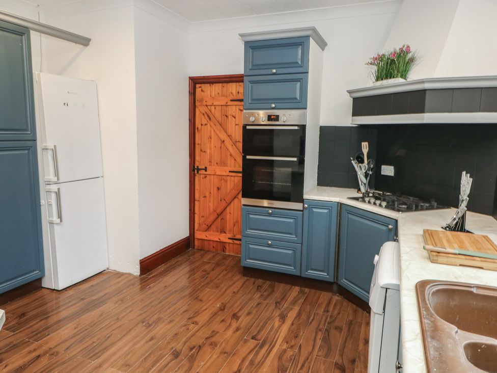 A kitchen with appliances and wooden flooring at Maes Hyfryd in Clynderwen
