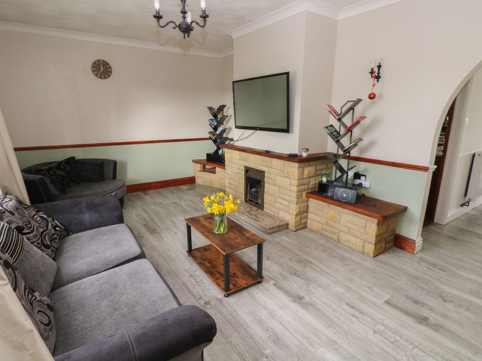 A living room with a sofa, table, and television at Maes Hyfryd, Efailwen near Maenclochog