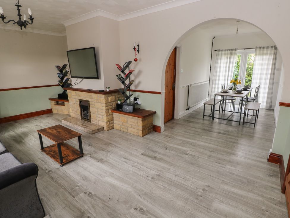 A living room with a fireplace and dining table at Maes Hyfryd in Efailwen near Maenclochog