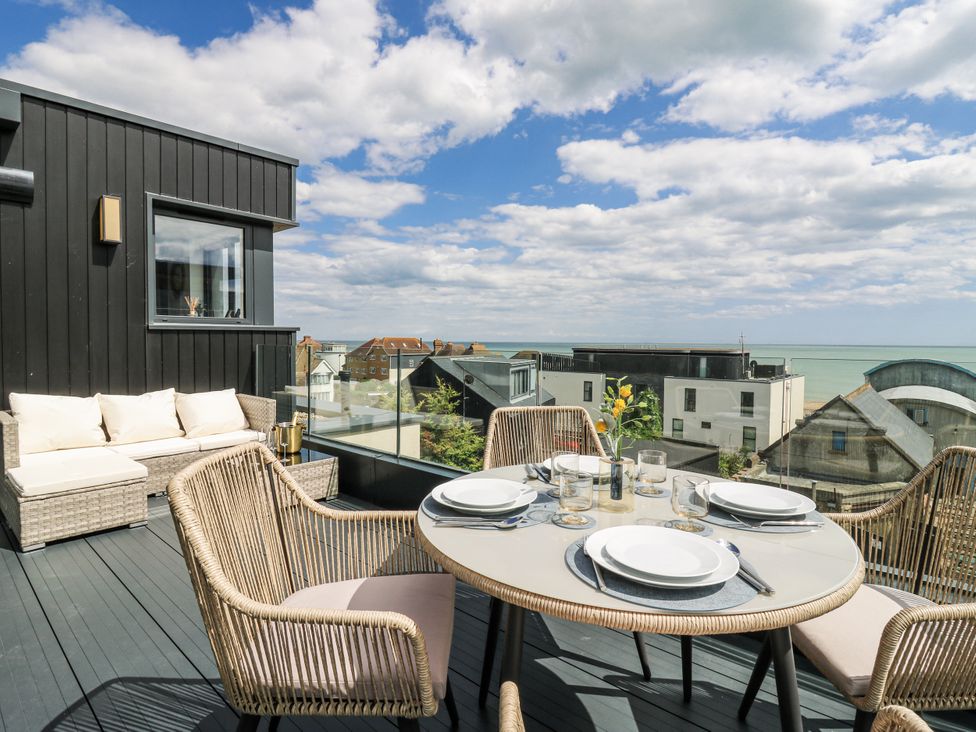 An outdoor terrace with a dining table and chairs overlooking the sea at Flat 4 in Hythe