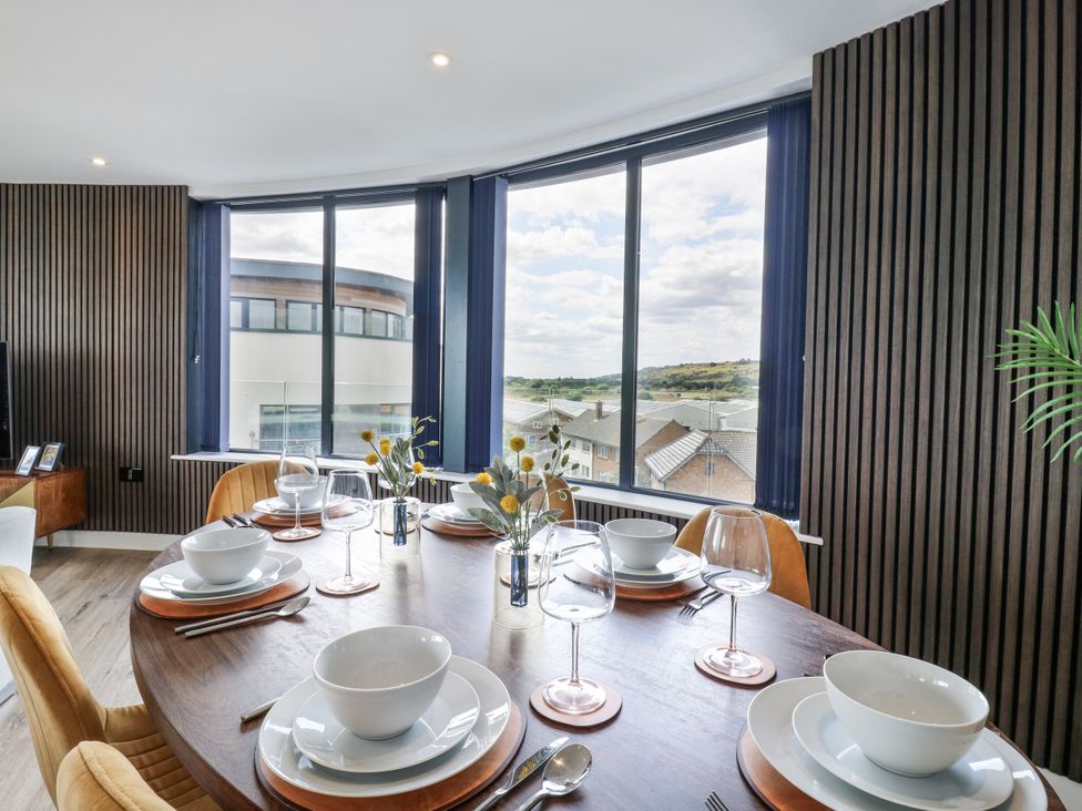 A dining room with a wooden table set for meals at Flat 4 in Hythe