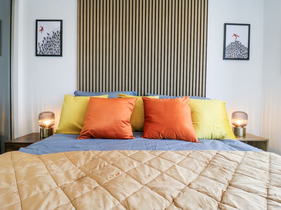 A bedroom with a bed and colorful pillows at Flat 4 in Hythe