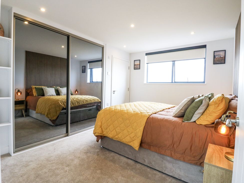 A bedroom with a bed and mirror at Flat 4 Hythe