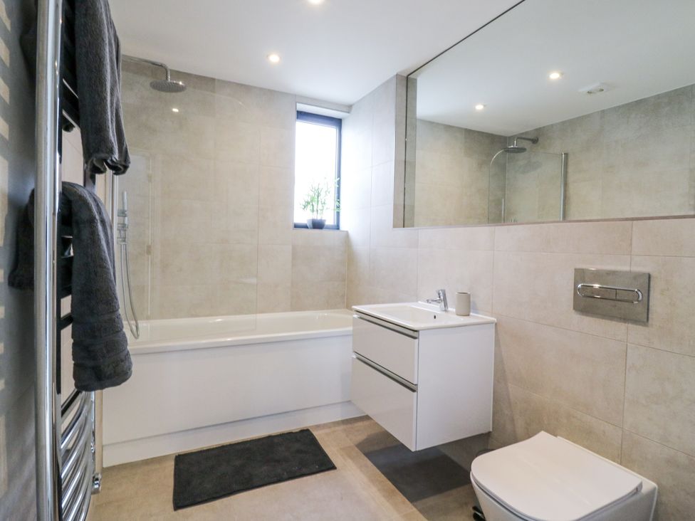 A bathroom with a bathtub, shower, and sink at Flat 4 in Hythe