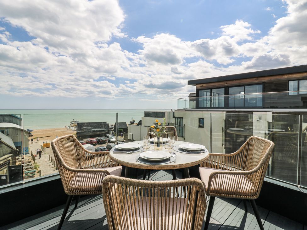 An outdoor patio with a table and chairs overlooking the ocean at Flat 4 in Hythe