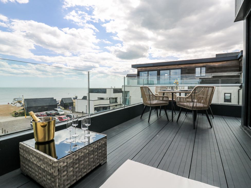 A balcony with a glass table and chairs overlooking the sea at Flat 4 in Hythe