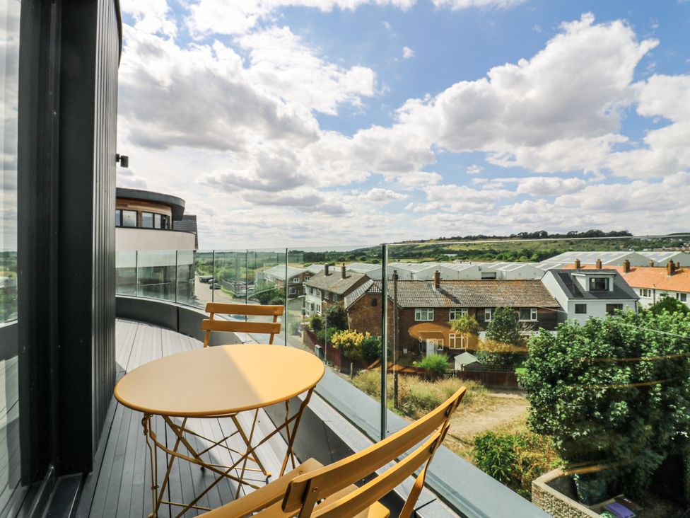 A balcony with table and chairs overlooking houses and landscape at Flat 4 in Hythe
