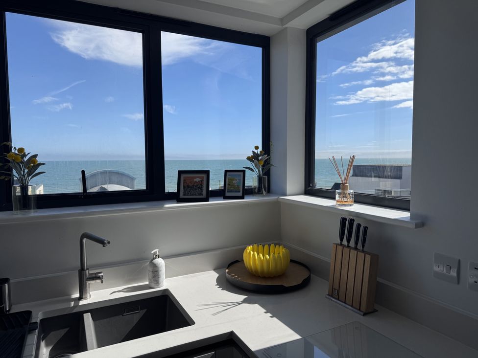 A kitchen with a sink, knife block, and windows overlooking the sea at Flat 4 Hythe