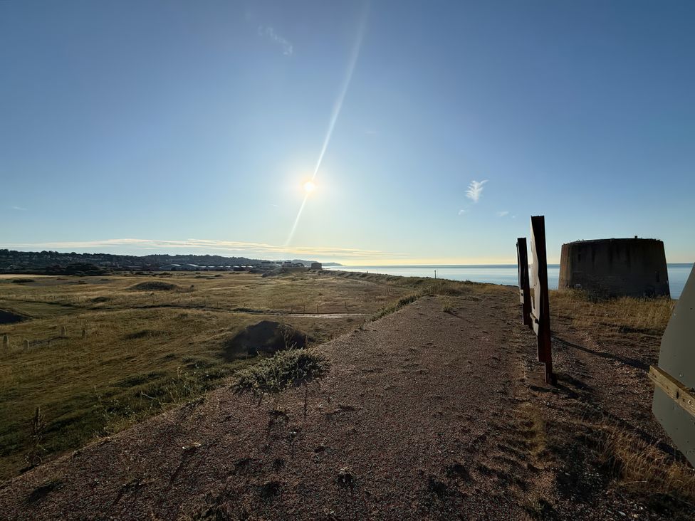 A view of the coast with a sun above and a bunker at Flat 4 Hythe