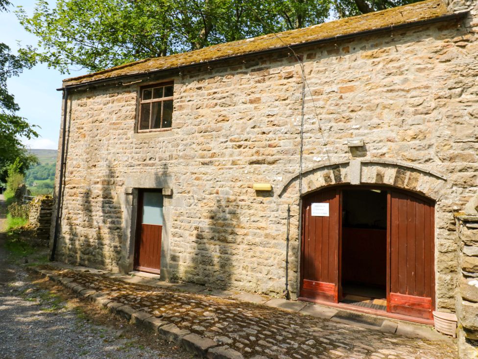 An outdoor view of a stone building with wooden doors at West Barn