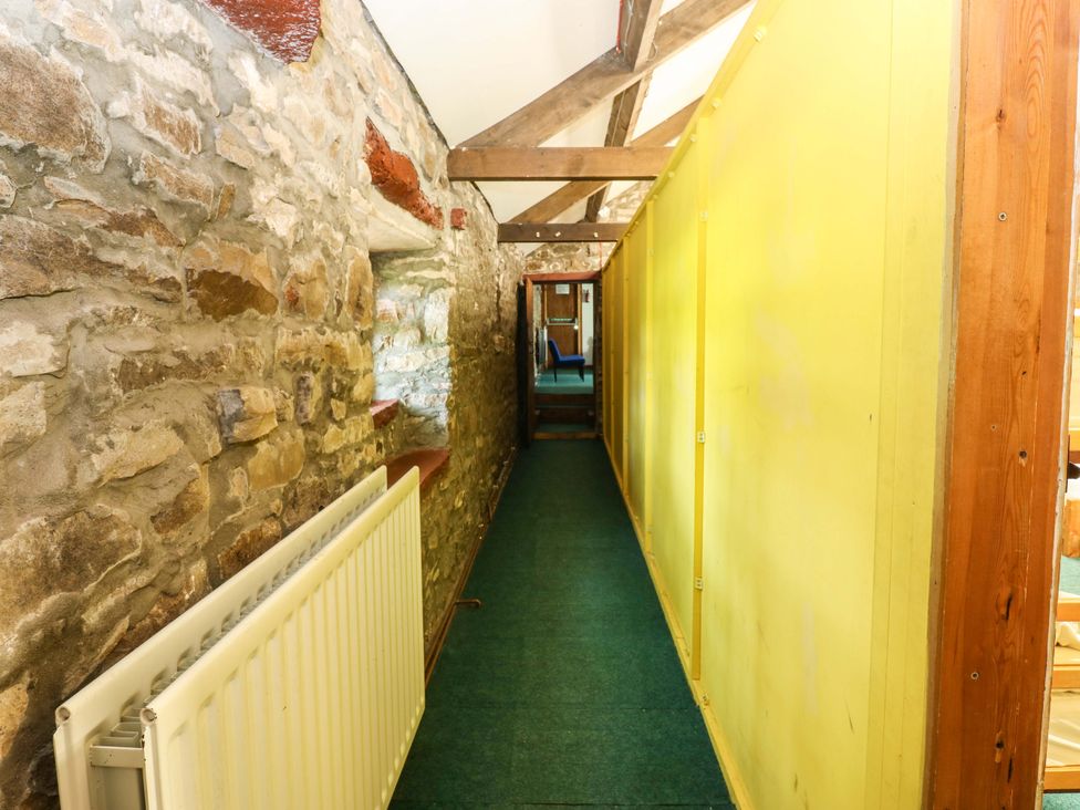 A hallway with stone walls and a yellow panel at West Barn
