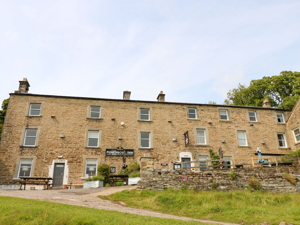 A building with a sign and outdoor seating at West Barn 