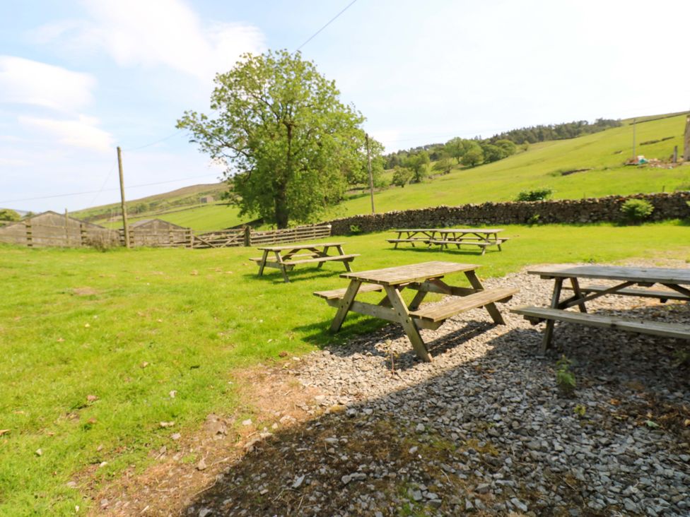 An outdoor area with picnic tables and a tree at West Barn 