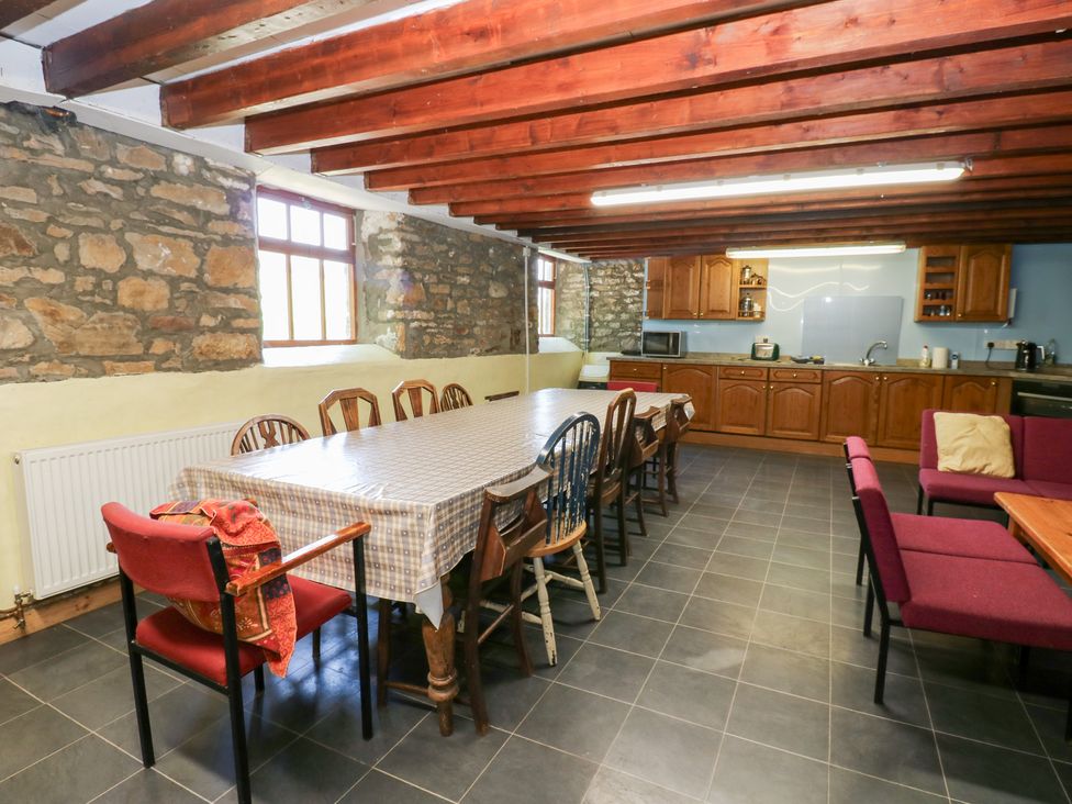 A dining room with a large table and kitchen area at East Barn Bunkhouse