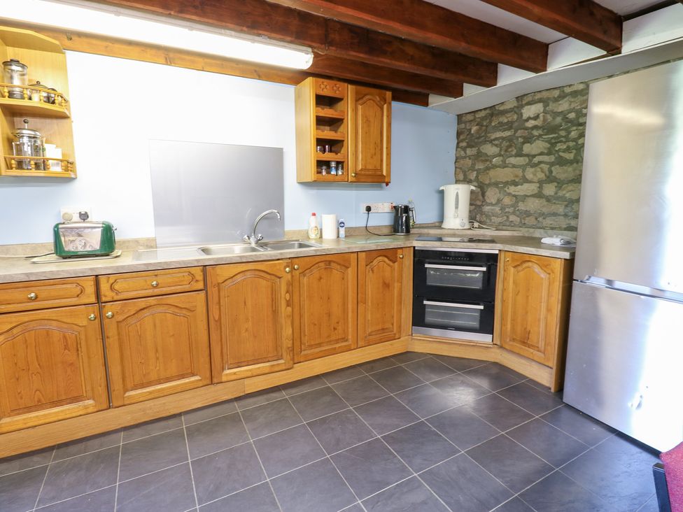 A kitchen with wooden cabinets and appliances at East Barn Bunkhouse