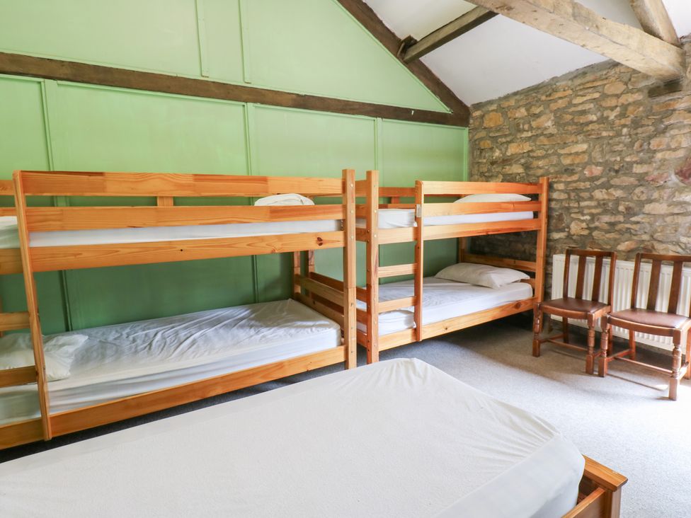 A bedroom with bunk beds and wooden chairs at East Barn Bunkhouse in 